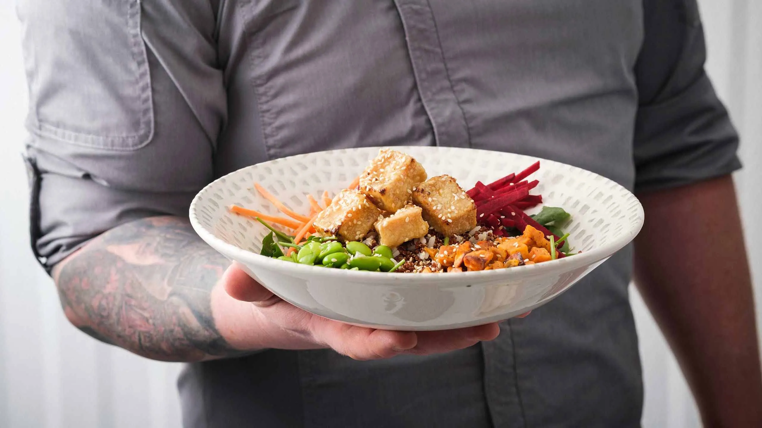 Chef holding white bowl of crispy tofu salad