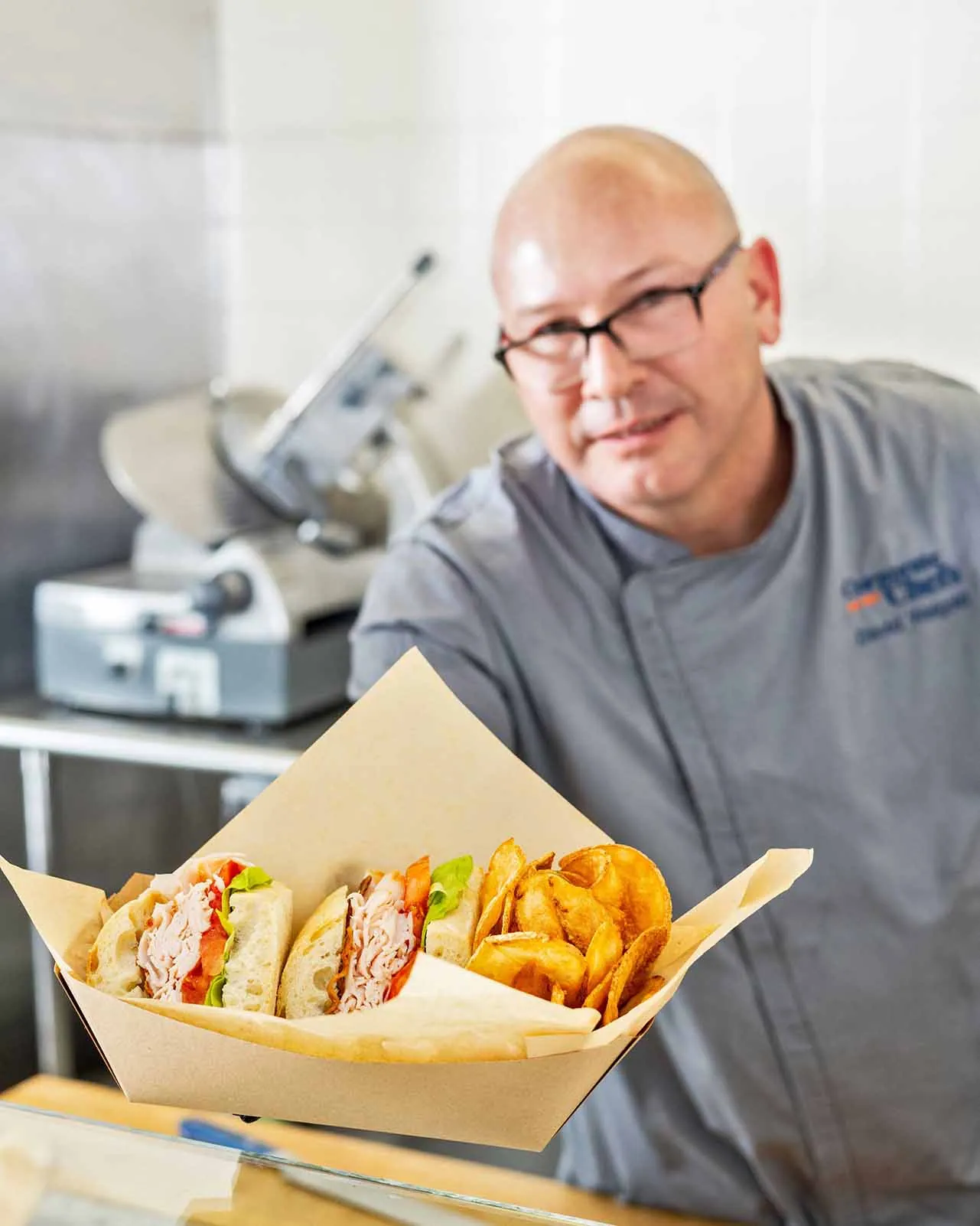 Employee smiling while passing a basket of food to customer at serving line